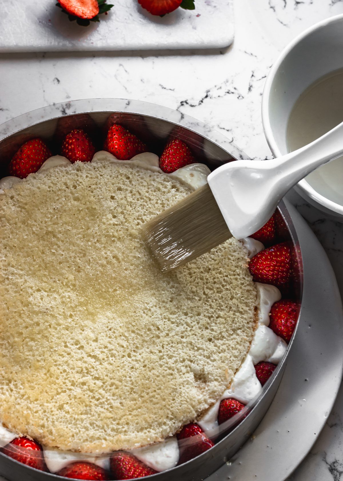 הכנת עוגת תותים צרפתית- פרזייה- מברישים בסירופ סוכר בעזרת מברשת את שכבת הג׳ינואז העליונה
