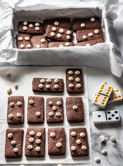 עוגיות דומינו מבצק פריך בטעם קקאו מעל שוקולד צ׳יפס לבן מסודר כמו נקודות על קוביות דומינו